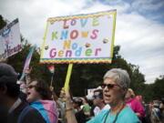 FILE - Barbara Dale, from Atlanta, mother of a transgender child, waves sign reading "Love Knows No Gender" at Gay Pride Transgender March at Piedmont Park in the city's Midtown District in Atlanta, Ga, Saturday, Oct. 12, 2019. Transgender medical treatment for children and teens is increasingly under attack in many states, labeled child abuse and subject to criminalizing bans. But it has been available in the United States for more than a decade and is endorsed by major medical associations.