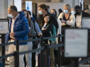 Passengers wait in line at the security checkpoint at Ronald Reagan Washington National Airport, Tuesday, April 19, 2022, in Arlington, Va. A federal judge's decision to strike down a national mask mandate was met with cheers on some airplanes but also concern about whether it's really time to end the order sparked by the COVID-19 pandemic.