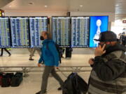 FILE - Travelers walk through Seattle-Tacoma International Airport on Friday, April 1, 2022 in Seattle. On Monday, April 18, 2022, a federal judge in Florida voided the national mask mandate covering airplanes and other public transportation saying it exceeded the authority of U.S. health officials. (AP Photo/Ted S.