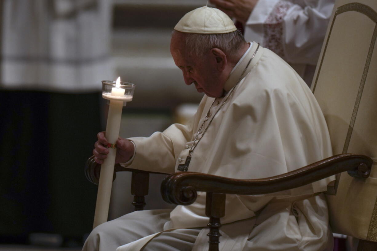 Pope Francis holds a Paschal candle as he presides over a Easter vigil ceremony at St. Peter's Basilica at the Vatican, Saturday, April 16, 2022.