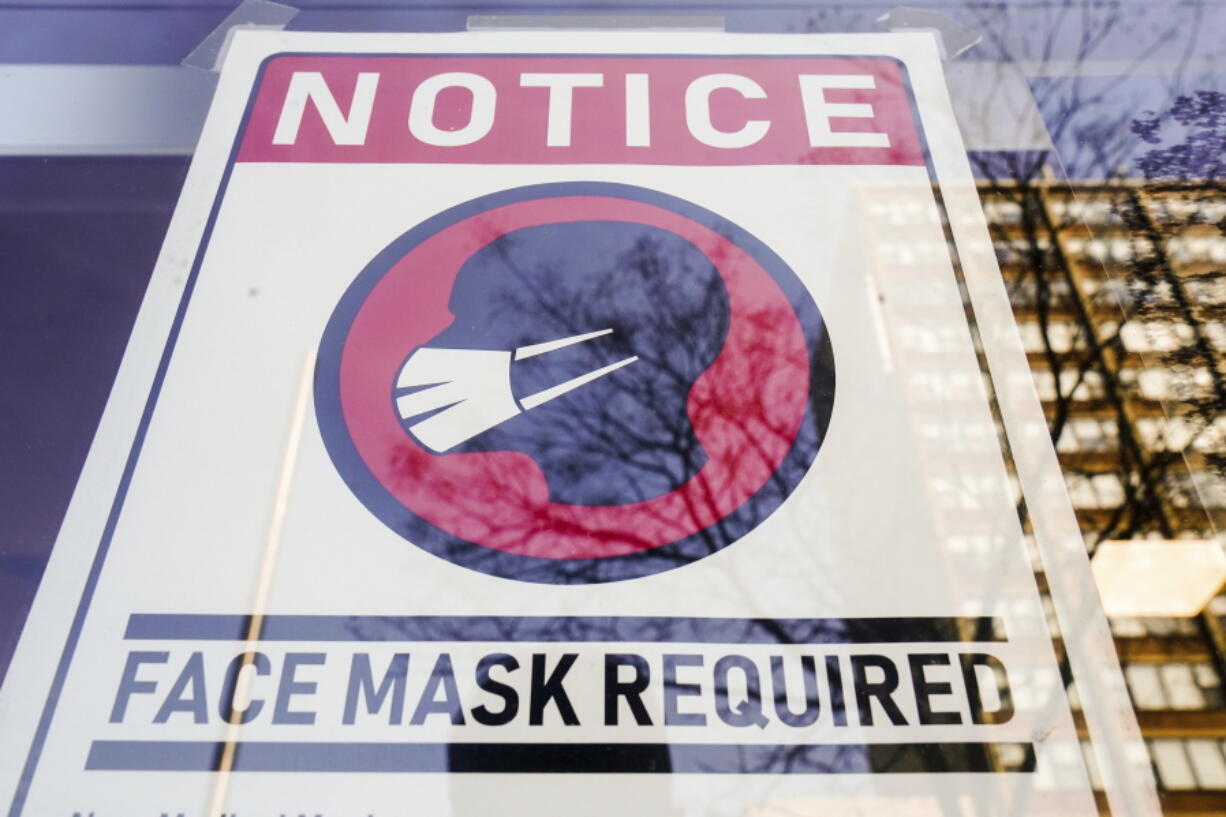 FILE - A sign requiring masks as a precaution against the spread of the coronavirus on a store front in Philadelphia, is seen Feb. 16, 2022. Philadelphia is reinstating its indoor mask mandate after reporting a sharp increase in coronavirus infections, Dr. Cheryl Bettigole, the city's top health official, announced Monday, April 11, 2022. Confirmed COVID-19 cases have risen more than 50% in 10 days, the threshold at which the city's guidelines call for people to wear masks indoors.