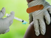 FILE - A health worker administers a dose of COVID-19 vaccine during a vaccination clinic in Reading, Pa. COVID-19 vaccinations are at a critical juncture as companies test whether new approaches like combination shots or nasal drops can keep up with a mutating coronavirus -- even though it's not clear if any change is needed.