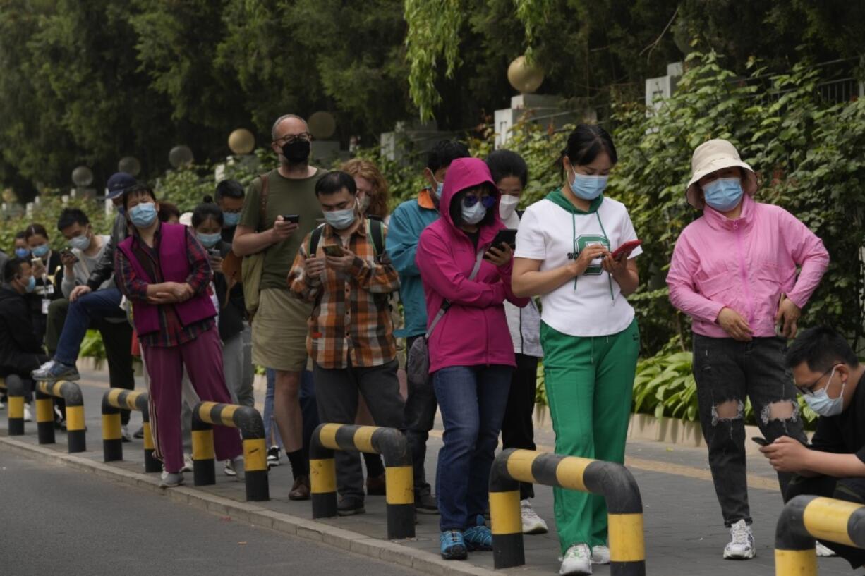 Residents wearing masks line up for mass COVID testing in Chaoyang District on Monday, April 25, 2022, in Beijing.