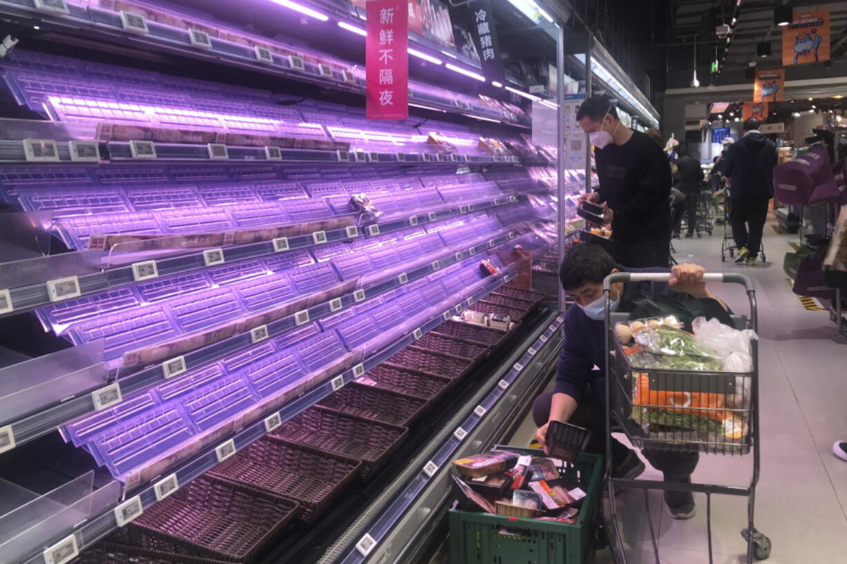 FILE - Customers look through empty shelves at a supermarket in Shanghai, China, on March 30, 2022. Residents of Shanghai are struggling to get meat, rice and other food supplies under anti-coronavirus controls that confine most of its 25 million people in their homes, fueling frustration as the government tries to contain a spreading outbreak.