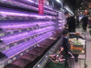 FILE - Customers look through empty shelves at a supermarket in Shanghai, China, on March 30, 2022. Residents of Shanghai are struggling to get meat, rice and other food supplies under anti-coronavirus controls that confine most of its 25 million people in their homes, fueling frustration as the government tries to contain a spreading outbreak.