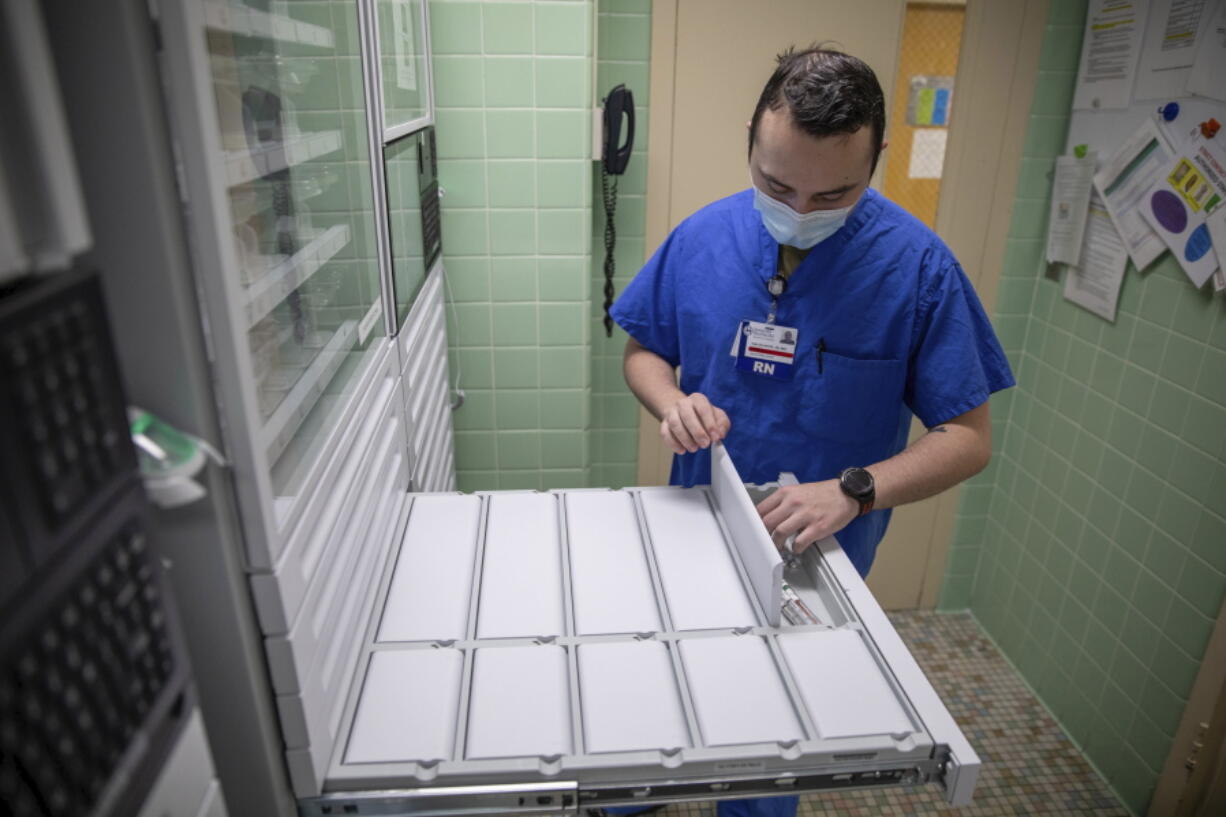 In this image provided by the U.S. Army, U.S. Air Force 2nd Lt. Kaelan Hayes, a clinical nurse assigned to the military medical team deployed to Brockton, Mass., gathers medication as part of the COVID-19 response operations at Signature Healthcare Brockton Hospital, March 15, 2022. (Sgt. Kaden D. Pitt/U.S.