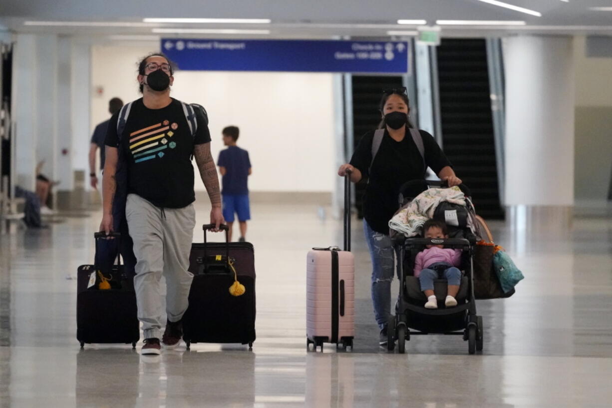 Travelers roll their luggage at a baggage claim area at Los Angeles International Airport Monday, April 25, 2022, in Los Angeles. A week earlier, a federal judge in Florida struck down the requirement to wear a mask in airports and during flights. That rule, designed to limit the spread of COVID-19, was due to expire anyway on May 3.