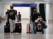 Travelers roll their luggage at a baggage claim area at Los Angeles International Airport Monday, April 25, 2022, in Los Angeles. A week earlier, a federal judge in Florida struck down the requirement to wear a mask in airports and during flights. That rule, designed to limit the spread of COVID-19, was due to expire anyway on May 3.