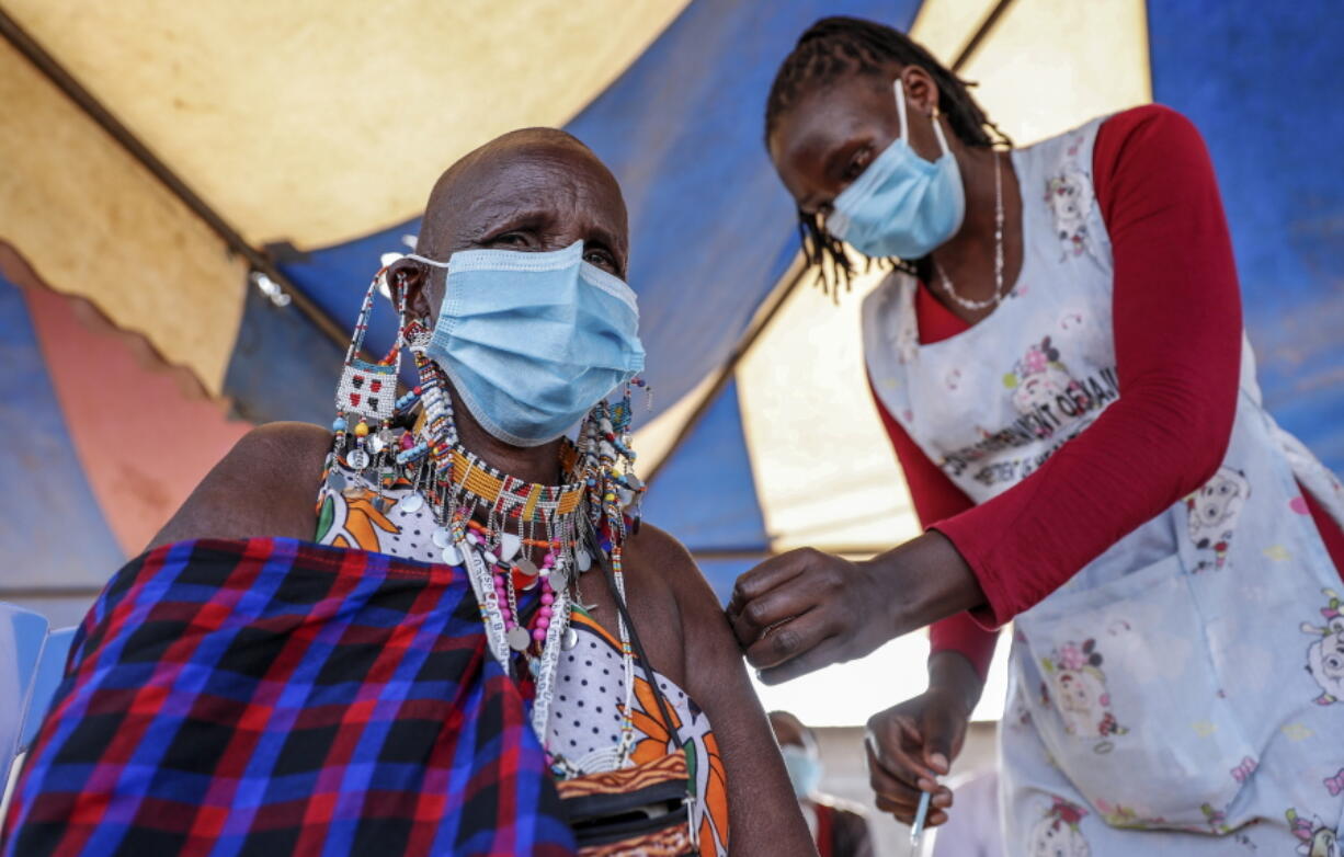 FILE - A Maasai woman receives the AstraZeneca coronavirus vaccine at a clinic in Kimana, southern Kenya on Aug. 28, 2021. The World Health Organization said Thursday, April 14, 2022 that the number of coronavirus cases and deaths in Africa have dropped to their lowest levels since the pandemic began, marking the longest decline yet seen in the disease.