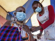 FILE - A Maasai woman receives the AstraZeneca coronavirus vaccine at a clinic in Kimana, southern Kenya on Aug. 28, 2021. The World Health Organization said Thursday, April 14, 2022 that the number of coronavirus cases and deaths in Africa have dropped to their lowest levels since the pandemic began, marking the longest decline yet seen in the disease.