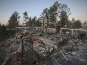 A two-story house continues to smolder following the McBride Fire in Ruidoso, New Mexico, on Thursday, April 14, 2022.   Authorities say firefighters have kept a wind-driven blaze from pushing further into a mountain community in the southern part of the state.