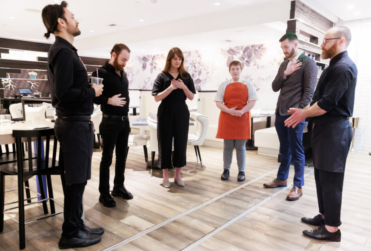 Server Jason Schweizer, far left, bartender Joe Beadle, owner and wellness director Deborah Friend Wilson, sous-chef Dorothy Allen, general manager Max Murtaugh and server Evan Hales, gather in a pre-shift meditation at The Lakehouse in Bellevue, Washington.