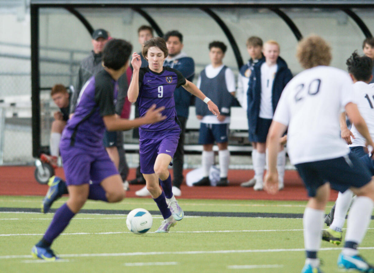 Columbia River's Alex Harris dribbles up the field against multiple Burlington-Edison defenders during the first half of the Class 2A state boys soccer semifinals on Friday.