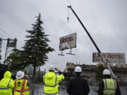 Port of Vancouver officials look on as the iconic sign for the Red Lion Hotel Vancouver at the Quay comes down Thursday morning. The sign removal is a part of a larger project to demolish the former hotel and rebuild Terminal 1, extending the district established by the new Waterfront Vancouver.