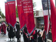 Graduate Zoe Minden, who earned a bachelor's degree in electrical engineering and won the Chancellor's Award for Student Achievement, steadies a banner before the Washington State University Vancouver commencement ceremony begins in 2022.