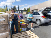 Volunteers Joe Pedron, left, Janis Yarbrough, center, and Sally Williams, all of Vancouver, prepare to load a car with donated food Tuesday during a drive-thru food distribution event at the Clark County Food Bank. Organizers of the National Association of Letter Carriers' food drive, slated for Saturday, hope to replenish the food bank's supply.