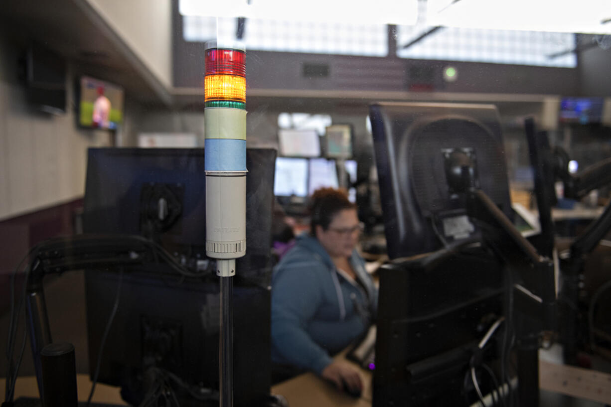 An illuminated orange light indicates Clark County dispatcher Robyn Hensley is on a call while working in downtown Vancouver. The Clark Regional Emergency Services Agency is hiring more dispatchers amid an increase in 911 calls across the growing county.