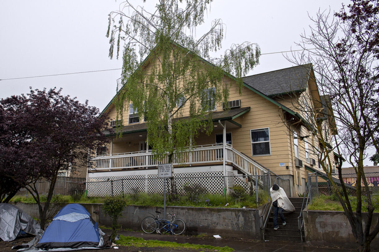 A man tries to take shelter from the wind and rain as he descends the stairs in front of the Share House in downtown Vancouver earlier this month. Several camps surrounding the Share House were removed for cleaning and sanitation by the city of Vancouver's Homeless Assistance Response Team throughout May. Before the camps were cleared, some 40 people were living there. People quickly returned to the area following the cleaning.