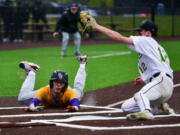 Columbia River senior Sam Boyle, left, slides into home and beats the tag from Tumwater pitcher Brayden Oram on Friday during River's 5-2 win against in the 2A District Championship at Ridgefield Outdoor Recreation Center.