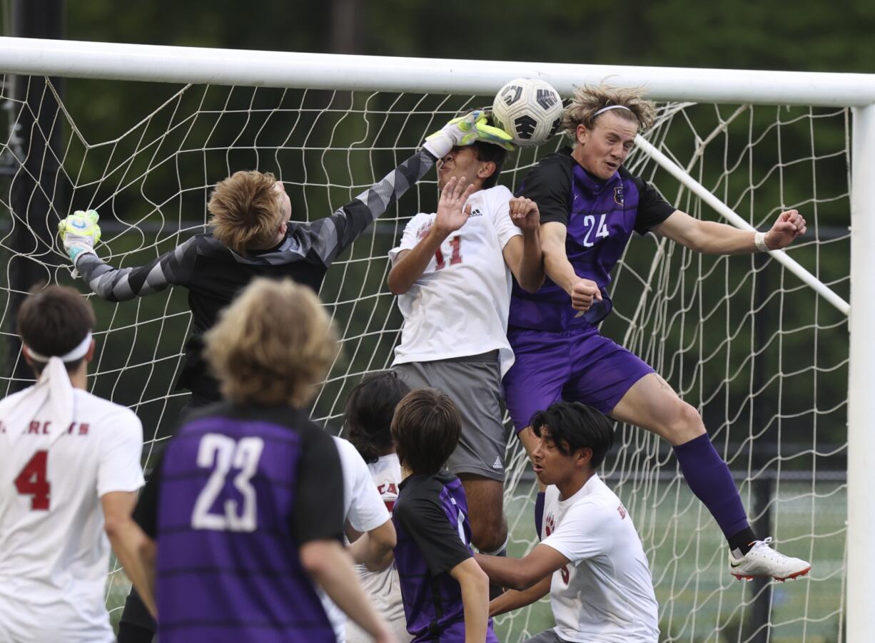 Columbia River's Alexander Brown, right, heads the ball at the goal as WF West's Hayden Sciera, left, and Ezra Bolin, center defend in the first round of the Class 2A state playoffs.