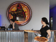 Kelsey Hood of Pied Piper Pizza, left, takes a call as assistant manager Misty Sadlier serves up fresh pizza on Thursday afternoon.