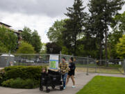 Atlas Shives, 2, of Vancouver, from left, joins his parents, Brendon and Lucia Shives, as they pass the Esther Short Park playground area Friday afternoon. Playground construction is scheduled to begin in June.