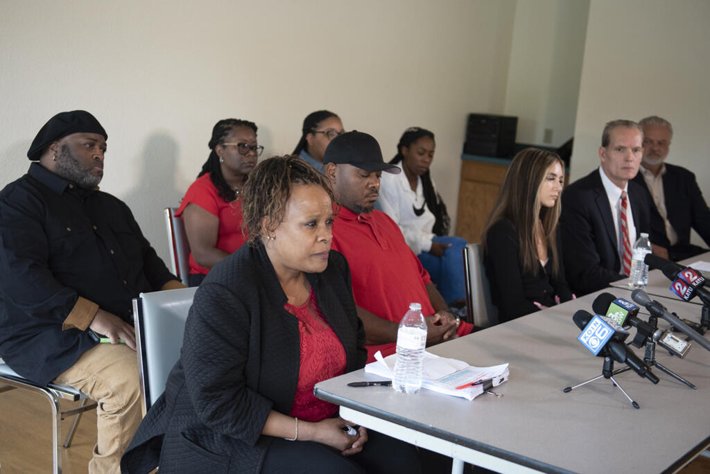 Tammi Bell, foreground with black sweater, mother of Kevin Peterson Jr., joins his father, Kevin Peterson Sr., black hat, and other family members during a press conference as they announce a lawsuit against the Clark County Sheriff's Office after the 21-year-old Black man was shot in 2020, as seen at the Aero Club on Thursday afternoon, May 26, 2022.