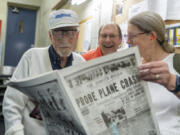 Frank Wallace, left, along with one of his sons John Wallace, center, and Deb Wallace look at a reproduction of a May 30, 1925 issue of The Dispatch-Herald of Erie, Pa. There were various stories plastered on its front page and, among them, had themes that would relate to his future career as someone who served in the Air Force during World War II.