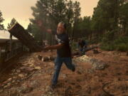 Chris Castillo throws a freshly-cut log as he and his cousins clear a wireline along a family member's home in Las Vegas, N.M., Monday, May 2, 2022. Wind-whipped flames are marching across more of New Mexico's tinder-dry mountainsides, forcing the evacuation of area residents and dozens of patients from the state's psychiatric hospital as firefighters scramble to keep new wildfires from growing.