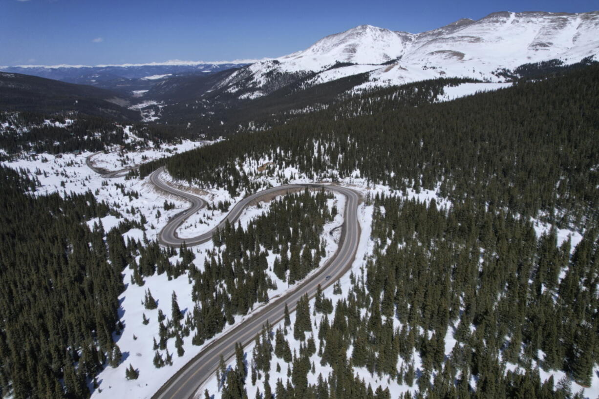 A road winds through the snow-covered Rocky Mountains at Hoosier Pass as seen from the air, Monday, April 18, 2022, near Blue River, Colo. Some drought-prone communities in the U.S. West are mapping snow by air to refine their water forecasts. It's one way water managers are adjusting as climate change disrupts weather patterns and makes current forecasting methods less reliable.