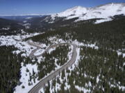 A road winds through the snow-covered Rocky Mountains at Hoosier Pass as seen from the air, Monday, April 18, 2022, near Blue River, Colo. Some drought-prone communities in the U.S. West are mapping snow by air to refine their water forecasts. It's one way water managers are adjusting as climate change disrupts weather patterns and makes current forecasting methods less reliable.