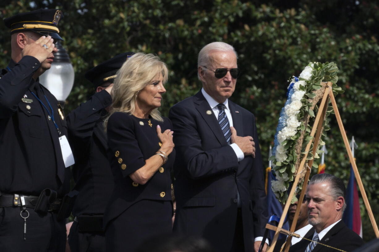 FILE - President Joe Biden and first lady Jill Biden put their right hand over their heart after placing flowers on a wreath during a ceremony honoring fallen law enforcement officers at the 40th annual National Peace Officers' Memorial Service at the U.S. Capitol in Washington, Oct. 16, 2021. Saluting on the left is James Smallwood, National Treasurer of the National Fraternal Order of Police.
