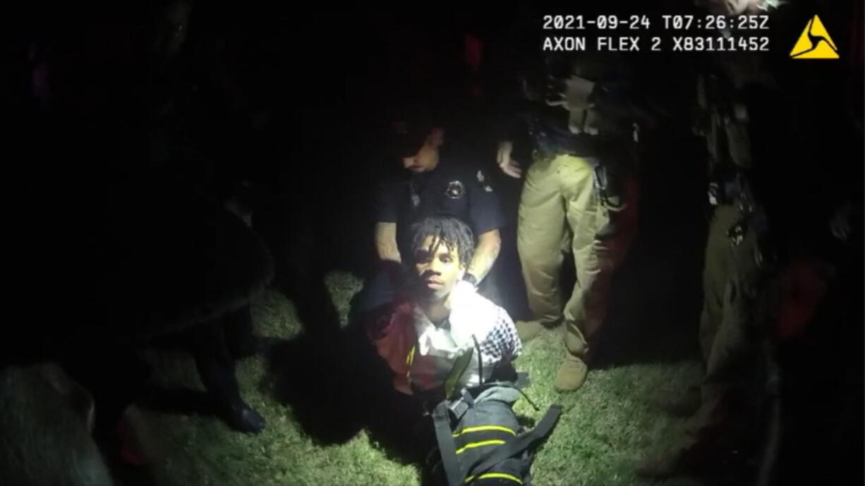 In this image from body camera video provided by Sedgwick County, police put Cedric "C.J." Lofton, 17, into a body-length restraining device called a WRAP outside his home in Wichita, Kan., on Sept. 24, 2021. His foster father, unable to deal with a teen who seemed to be in the throes of schizophrenia, had called Wichita police. When they arrived, Cedric refused to leave the porch and go with them; he was obstinate but afraid, meek but frantic.