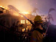 A firefighter works to put at a structure burning during a wildfire Wednesday, May 11, 2022, in Laguna Niguel, Calif. (AP Photo/Marcio J.