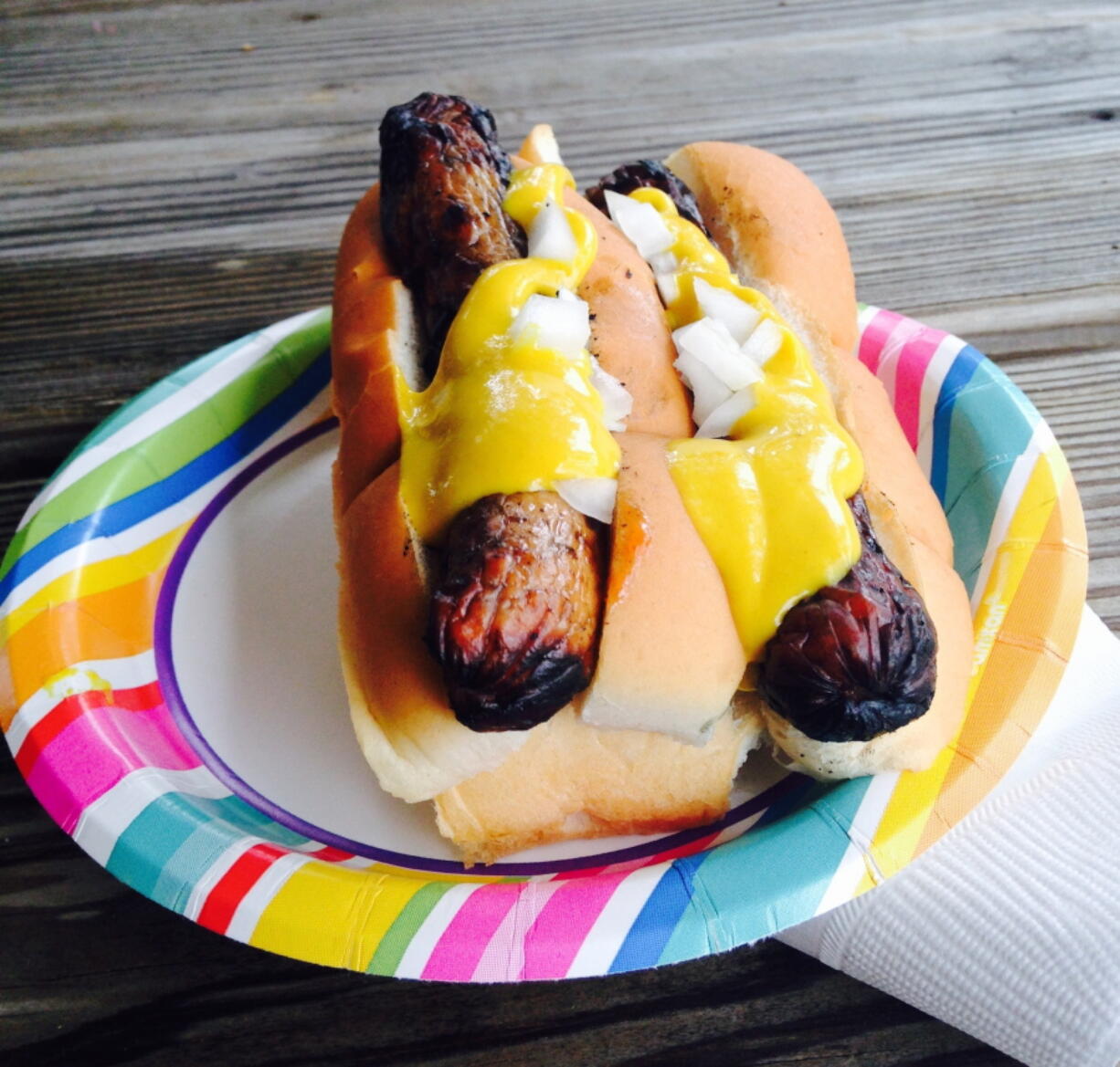 Yellow mustard on top of a pair of grilled hotdogs. Mustards are made around the world and with all kinds of ingredients besides mustard seeds. Try picking up local mustards when you travel.