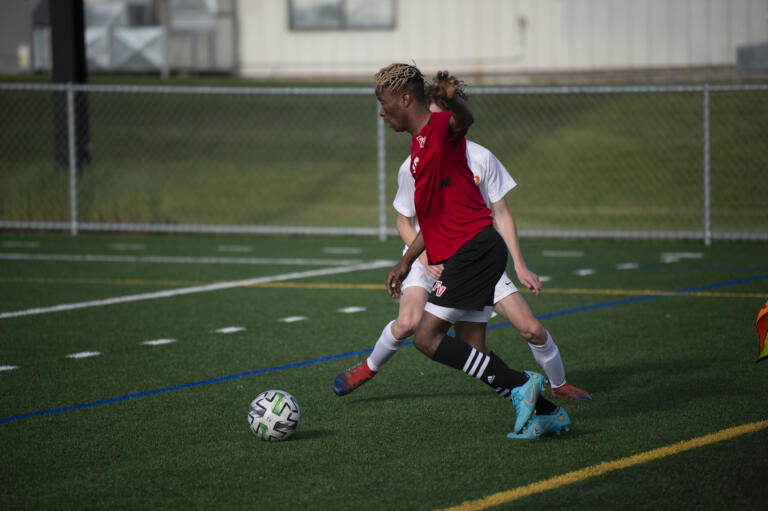 Fort Vancouver's Morlai Sesay works around a Ridgefield defender during the Trappers' 2-0 win over Ridgefield in 2A boys soccer district playoff on Saturday, May 14, 2022.