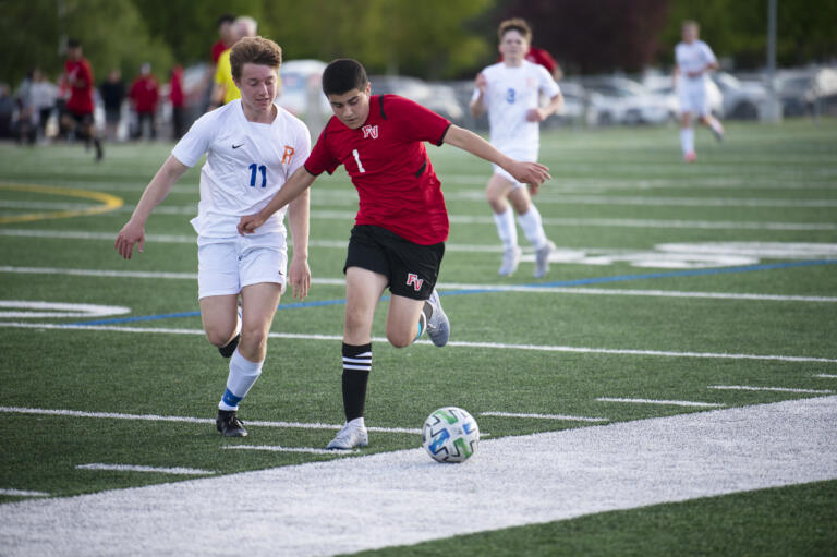 Fort Vancouver's Ernesto Coria Zavala (1) works against Ridgefield's Ashton Wagner during the Trappers' 2-0 win over Ridgefield in 2A boys soccer district playoff on Saturday, May 14, 2022.