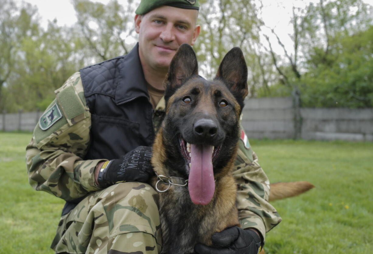 Sgt. 1st Class Balazs Nemeth poses with his bomb-sniffing dog Logan on April 28 at the garrison of the ordnance-disposal and warship regiment of the Hungarian Defense Forces in Budapest. Logan, a 2-year-old Belgian shepherd, has received a second chance after being rescued from abusive owners: He's been recruited to serve in an elite military bomb squad.