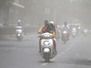 A woman covers her face with a scarf to protect from heat wave rides through a dust storm in Ahmedabad, India, on Saturday.