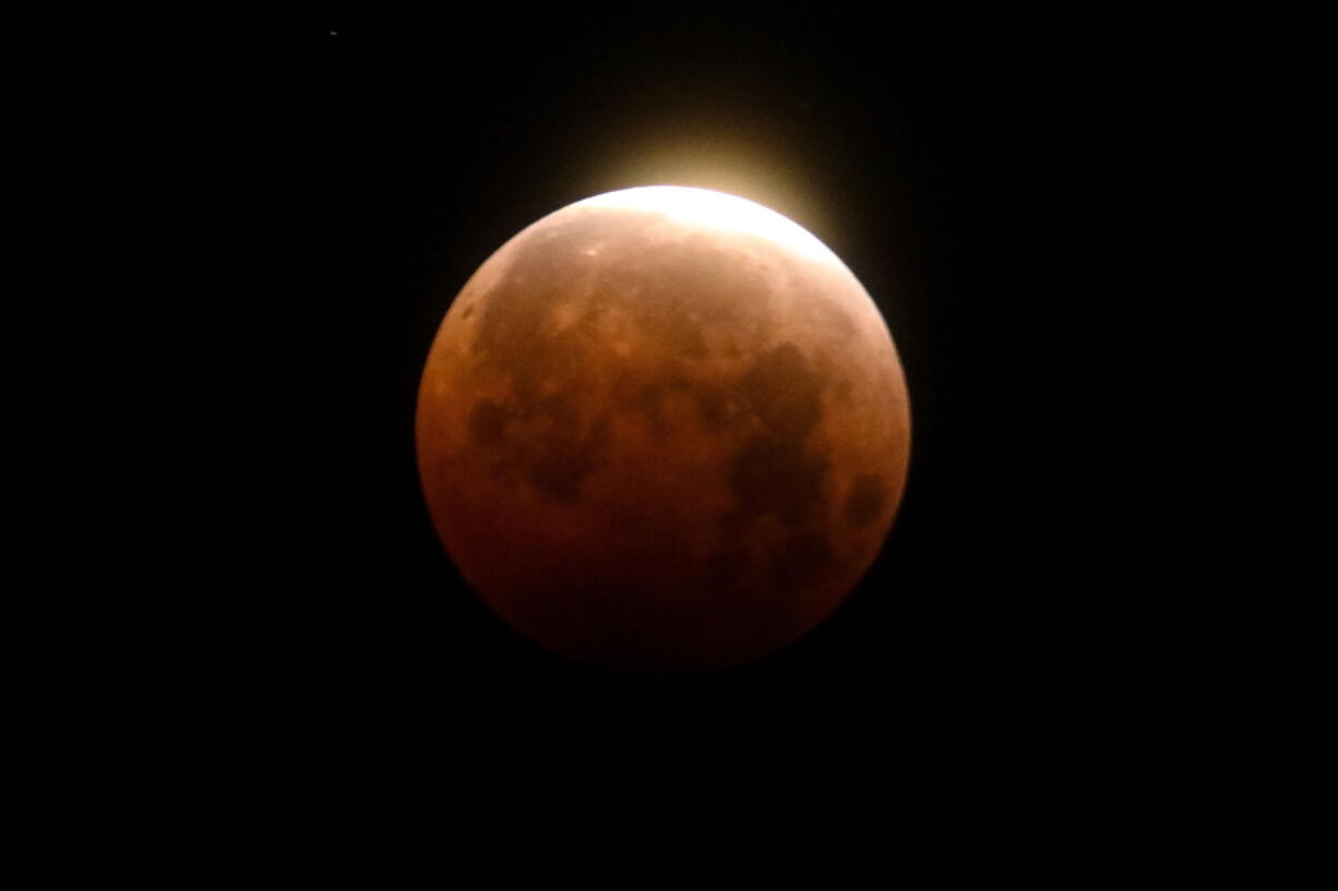 FILE - Light shines from a total lunar eclipse over Santa Monica Beach in Santa Monica, Calif., Wednesday, May 26, 2021. A total lunar eclipse will grace the night skies this weekend, providing longer than usual thrills for stargazers across North and South America. The celestial action unfolds Sunday night, May 15, 2022 into early Monday morning, with the moon bathed in the reflected red and orange hues of Earth's sunsets and sunrises for about 1 1/2 hours, the longest totality of the decade. It will be the first so-called blood moon in a year.(AP Photo/Ringo H.W.