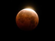 FILE - Light shines from a total lunar eclipse over Santa Monica Beach in Santa Monica, Calif., Wednesday, May 26, 2021. A total lunar eclipse will grace the night skies this weekend, providing longer than usual thrills for stargazers across North and South America. The celestial action unfolds Sunday night, May 15, 2022 into early Monday morning, with the moon bathed in the reflected red and orange hues of Earth's sunsets and sunrises for about 1 1/2 hours, the longest totality of the decade. It will be the first so-called blood moon in a year.(AP Photo/Ringo H.W.