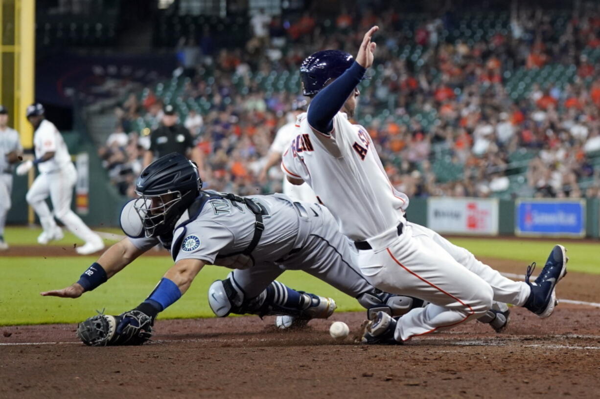 Seattle Mariners catcher Luis Torrens, left, reaches for the ball as Houston Astros' Alex Bregman scores during the sixth inning of a baseball game Wednesday, May 4, 2022, in Houston. (AP Photo/David J.