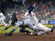 Seattle Mariners catcher Luis Torrens, left, reaches for the ball as Houston Astros' Alex Bregman scores during the sixth inning of a baseball game Wednesday, May 4, 2022, in Houston. (AP Photo/David J.