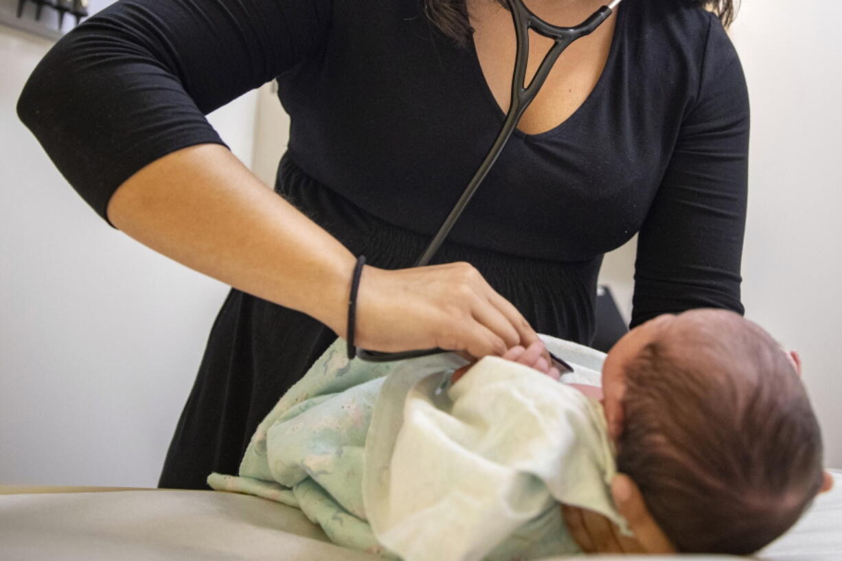 A pediatrician examines a newborn baby in her clinic in Chicago on Tuesday, Aug. 13, 2019. In a new policy statement released Monday, May 2, 2022, the American Academy of Pediatrics says it is putting all its guidance under the microscope to eliminate "race-based" medicine and resulting health disparities.