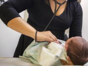 A pediatrician examines a newborn baby in her clinic in Chicago on Tuesday, Aug. 13, 2019. In a new policy statement released Monday, May 2, 2022, the American Academy of Pediatrics says it is putting all its guidance under the microscope to eliminate "race-based" medicine and resulting health disparities.