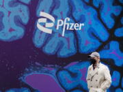 FILE - A man walks by Pfizer headquarters, Friday, Feb. 5, 2021 in New York.  Pfizer is spending more than $11 billion to buy the remaining portion of migraine treatment maker Biohaven Pharmaceuticals it does not already own. The New York drugmaker said Tuesday, May 10, 2022,  it will pay $148.50 in cash for each share of Biohaven, which makes Nurtec ODT for treating and preventing migraines and has another nasal spray under development.