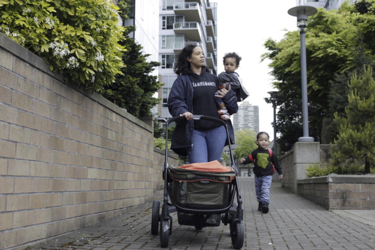 Callie Coppage, of Portland, Ore., takes a walk with her sons Anthony, 3, and Royal, 11 months near the Willamette River on May 13, 2022. Coppage received $7,000 from multimillionaire and "Twitter philanthropist" Bill Pulte after tweeting a photo of herself and her infant son, saying she had just left an abusive relationship and needed support. Coppage says the money helped her buy a used car, replace stolen car seats and get her life back on track.