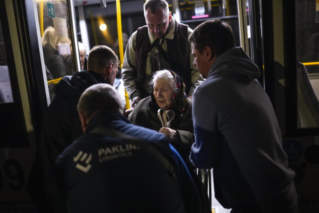 A woman who fled from the Azovstal steel plant in Mariupol is helped from a bus upon her arrival at a reception center for displaced people in Zaporizhzhia, Ukraine, late Sunday, May 8, 2022. Thousands of Ukrainians continue to leave Russian-occupied areas.