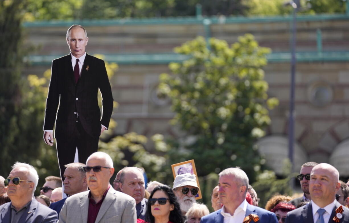 A man holds a picture of Russian President Vladimir Putin during the Victory Day ceremony in Belgrade, Serbia, Monday, May 9, 2022. People marking the 77th anniversary of the victory over Nazi Germany in WWII.