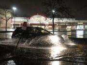 A vehicle drives through a flooded parking lot off of University Avenue in St. Paul, Minn., during severe weather, Wednesday, May 11, 2022.